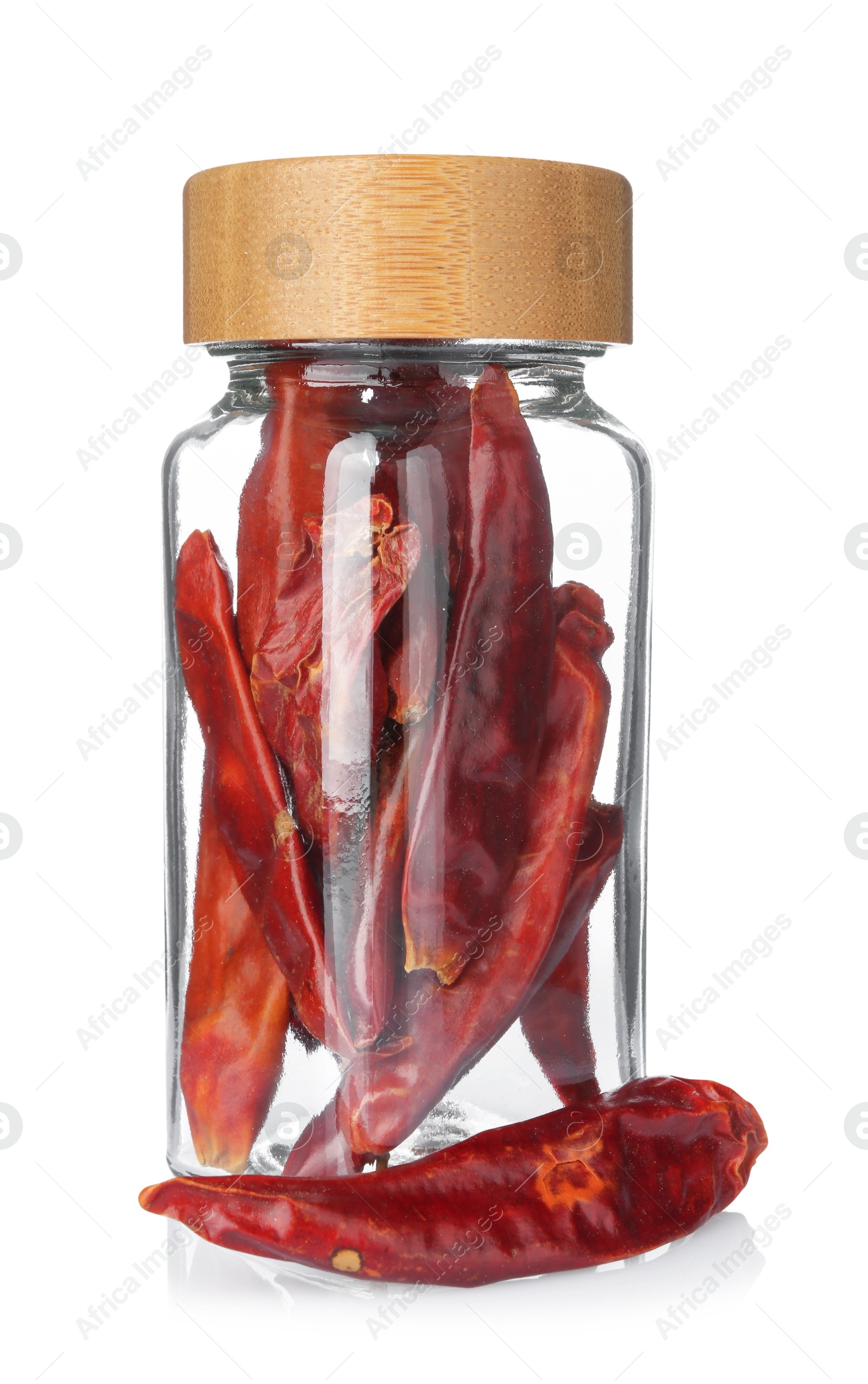 Photo of Dried red peppers in glass jar isolated on white. Aromatic spice