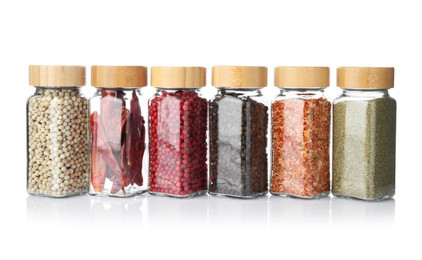 Photo of Different aromatic spices in glass jars isolated on white