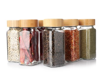 Photo of Different aromatic spices in glass jars isolated on white