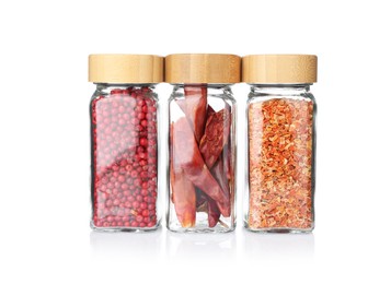 Photo of Different aromatic spices in glass jars isolated on white