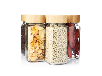 Photo of Different aromatic spices in glass jars isolated on white