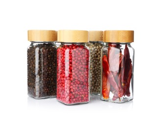 Photo of Different aromatic spices in glass jars isolated on white