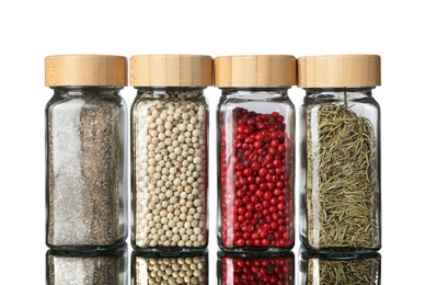 Photo of Many different aromatic spices in jars on mirror surface against white background