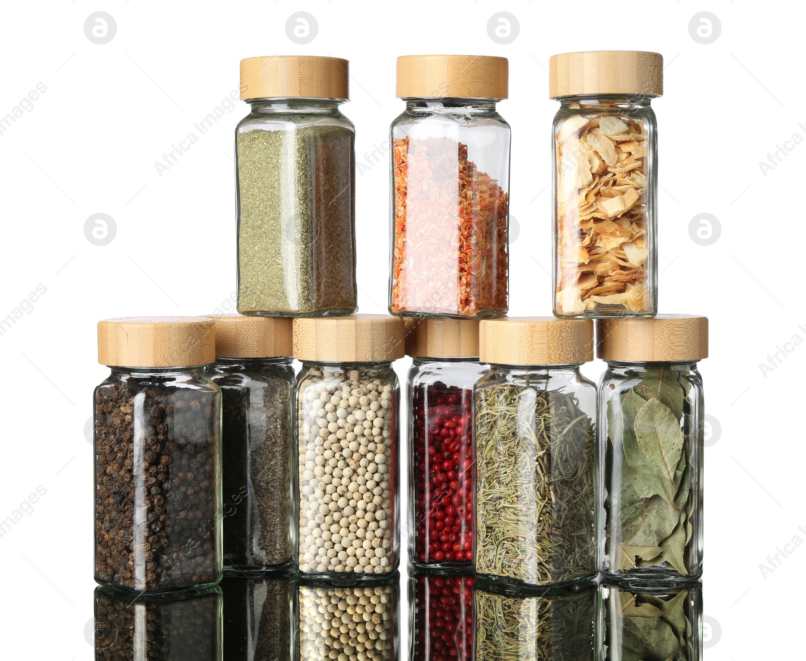 Photo of Many different aromatic spices in jars on mirror surface against white background