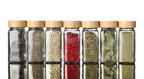 Photo of Many different aromatic spices in jars on mirror surface against white background
