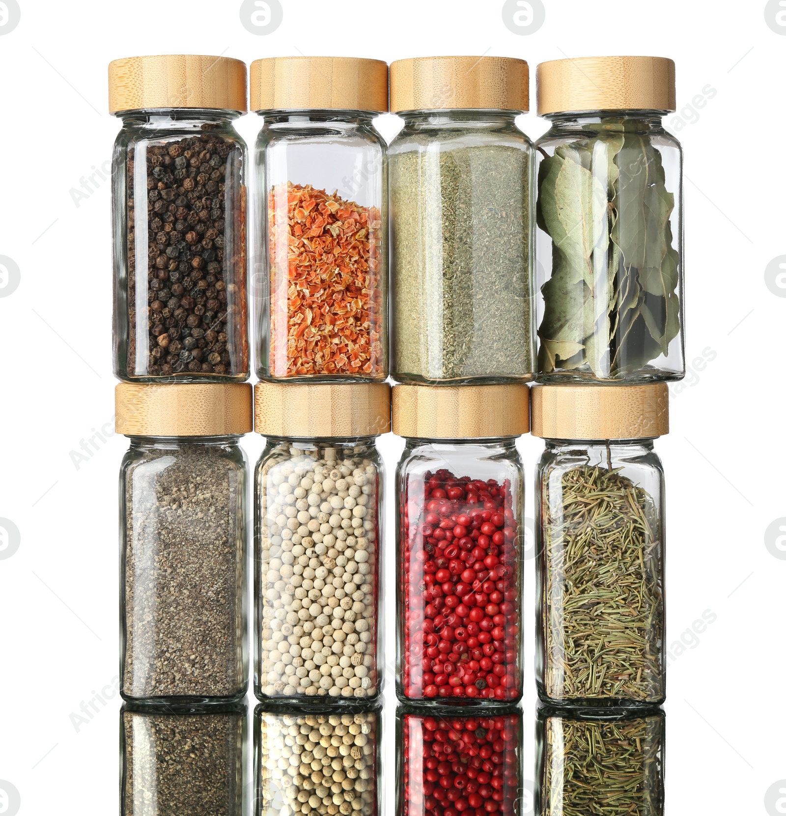 Photo of Many different aromatic spices in jars on mirror surface against white background