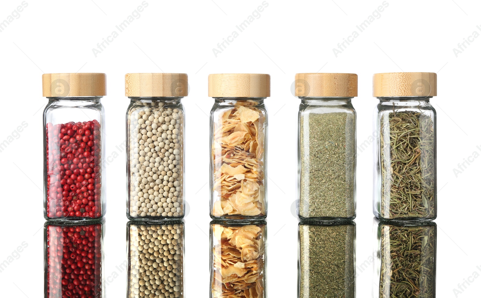 Photo of Many different aromatic spices in jars on mirror surface against white background