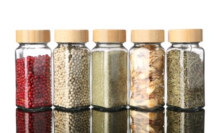 Photo of Many different aromatic spices in jars on mirror surface against white background
