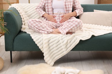 Photo of Woman suffering from cystitis symptoms on sofa at home, closeup