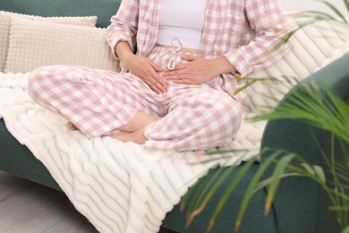 Photo of Woman suffering from cystitis symptoms on sofa at home, closeup