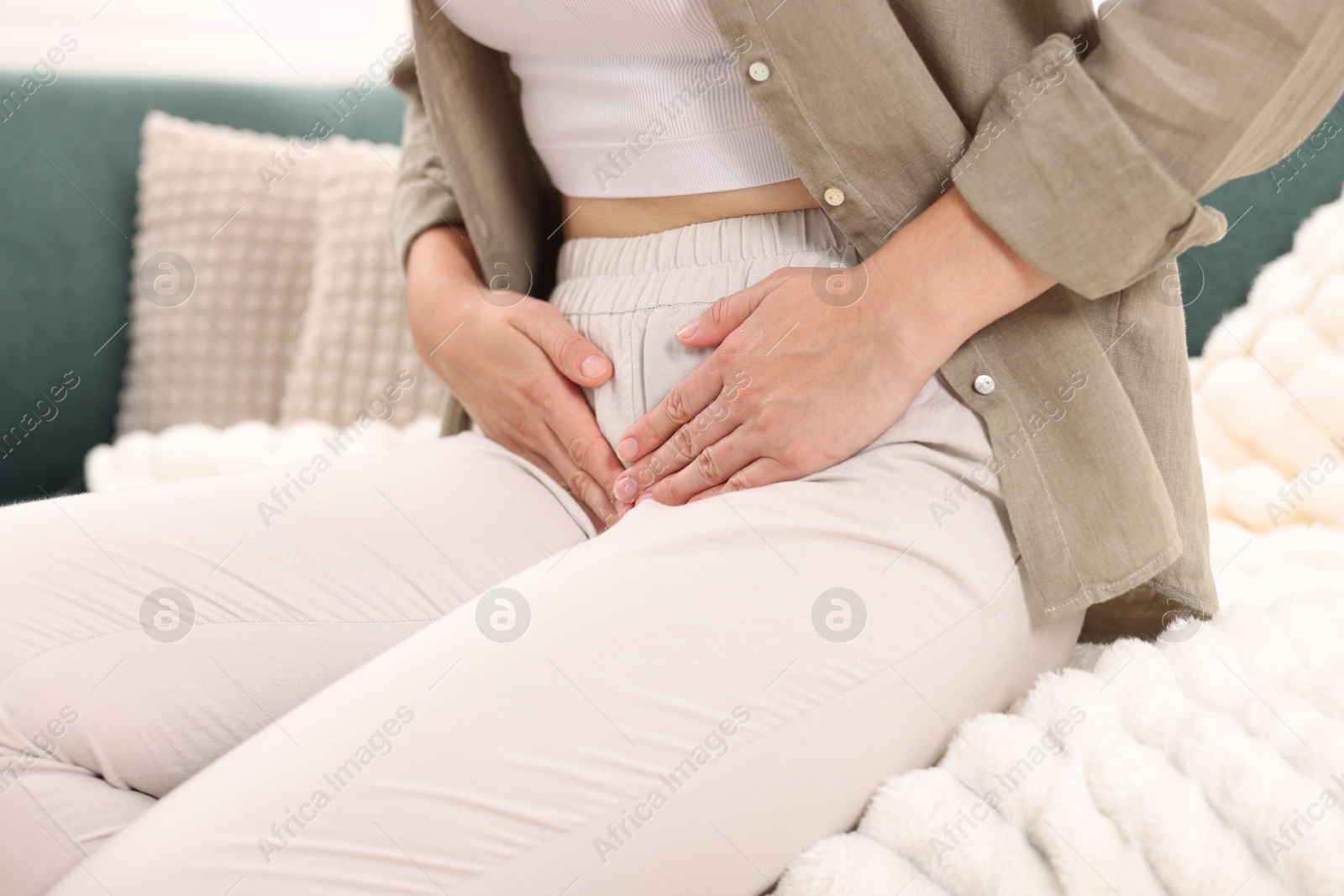 Photo of Woman suffering from cystitis symptoms on sofa at home, closeup