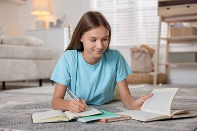 Photo of Teenage girl studying with books on floor in room. Homeschooling
