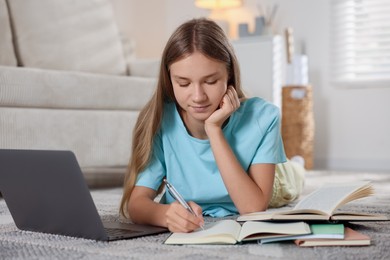 Photo of Teenage girl studying online on floor at home