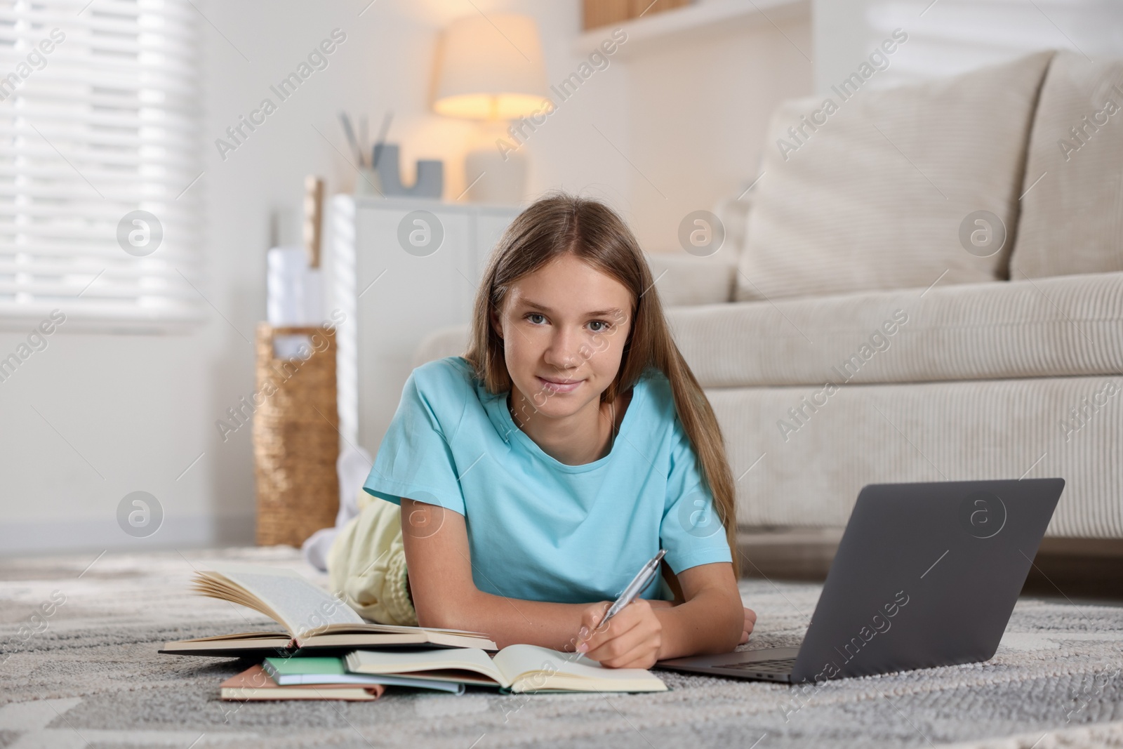 Photo of Teenage girl studying online on floor at home