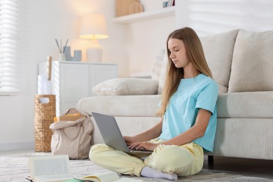 Photo of Teenage girl studying online with laptop on floor at home
