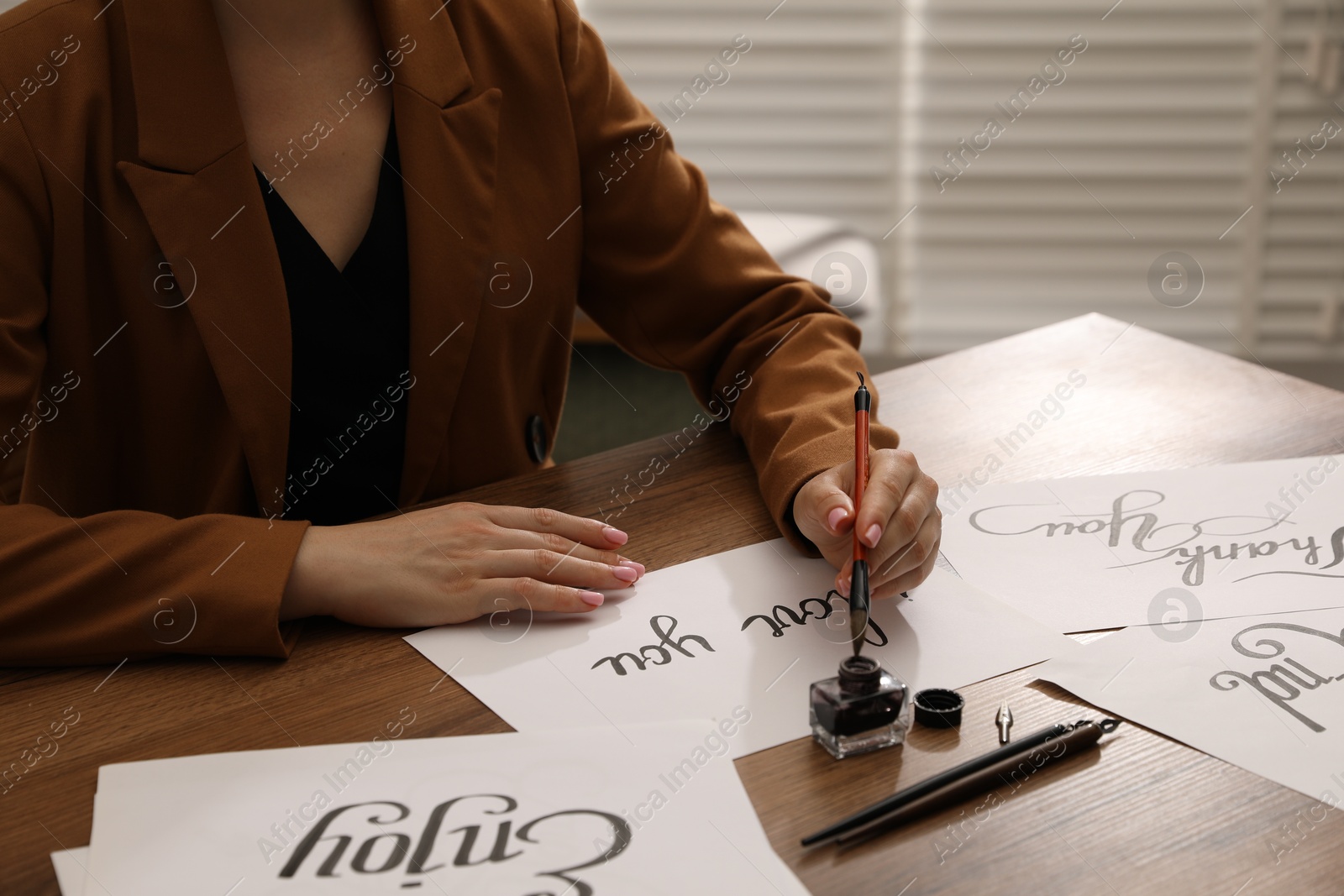 Calligraphy. Woman with brush writing phrase I Love You on sheet of paper at wooden table, closeup Photo of Calligraphy. Woman with brush writing phrase I Love You on sheet of paper at wooden table, closeup