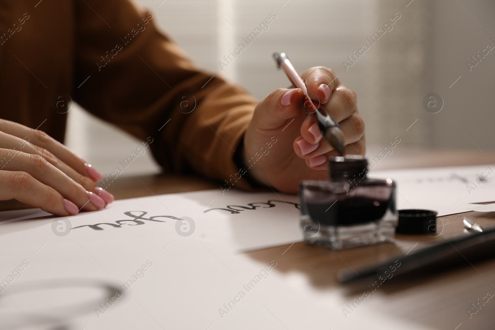 Photo of Calligraphy. Woman with brush, ink and handwritten cards at table, closeup