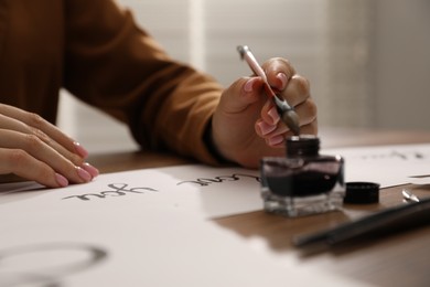 Photo of Calligraphy. Woman with brush, ink and handwritten cards at table, closeup