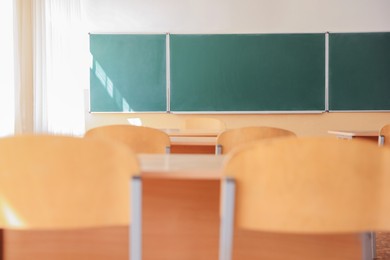 Photo of Desks with chairs and green chalkboard in classroom