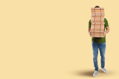 Image of Man holding many pizza boxes against beige background. Space for text