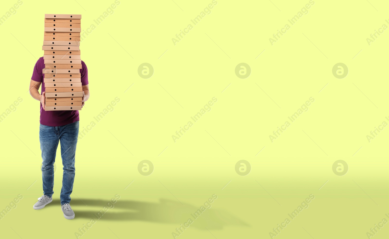 Man holding many pizza boxes against light green background. Banner design with space for text Image of Man holding many pizza boxes against light green background. Banner design with space for text