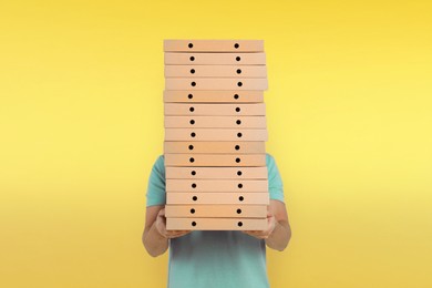 Image of Man holding many pizza boxes against yellow gradient background