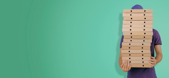 Image of Deliveryman holding many pizza boxes against turquoise gradient background. Banner design with space for text