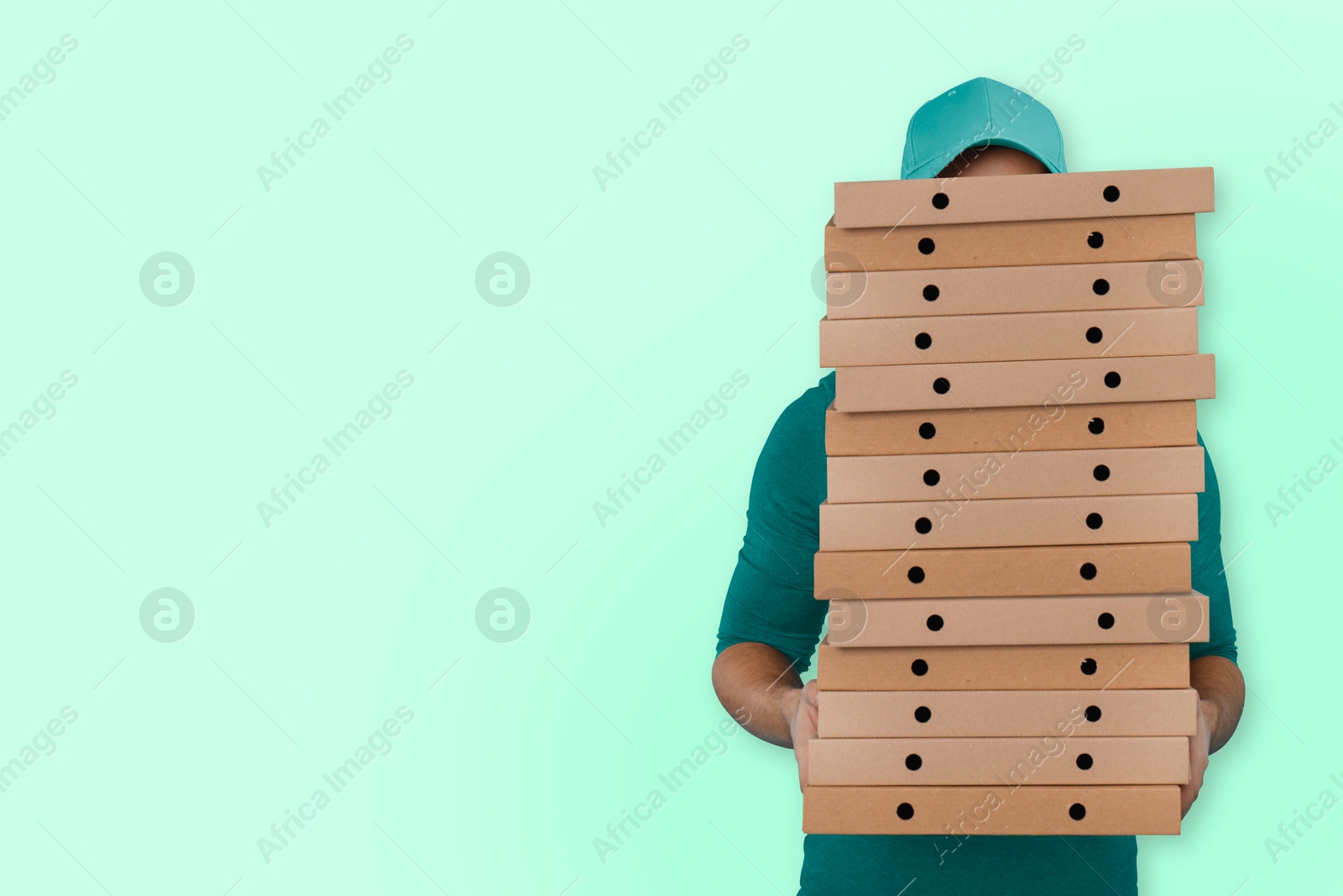 Deliveryman holding many pizza boxes against light blue background. Space for text Image of Deliveryman holding many pizza boxes against light blue background. Space for text