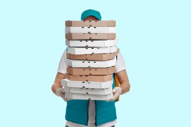Image of Deliveryman holding many pizza boxes against light blue background
