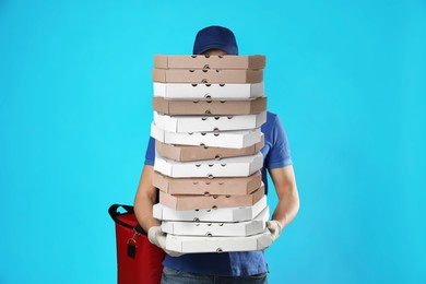 Image of Deliveryman holding many pizza boxes against light blue background