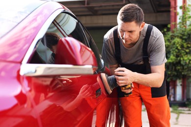 Photo of Man polishing car with orbital polisher outdoors