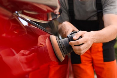 Photo of Man polishing car with orbital polisher outdoors, closeup