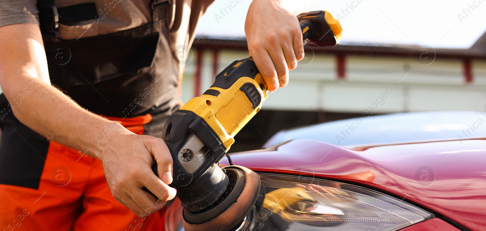 Photo of Man polishing car headlight with orbital polisher outdoors, closeup