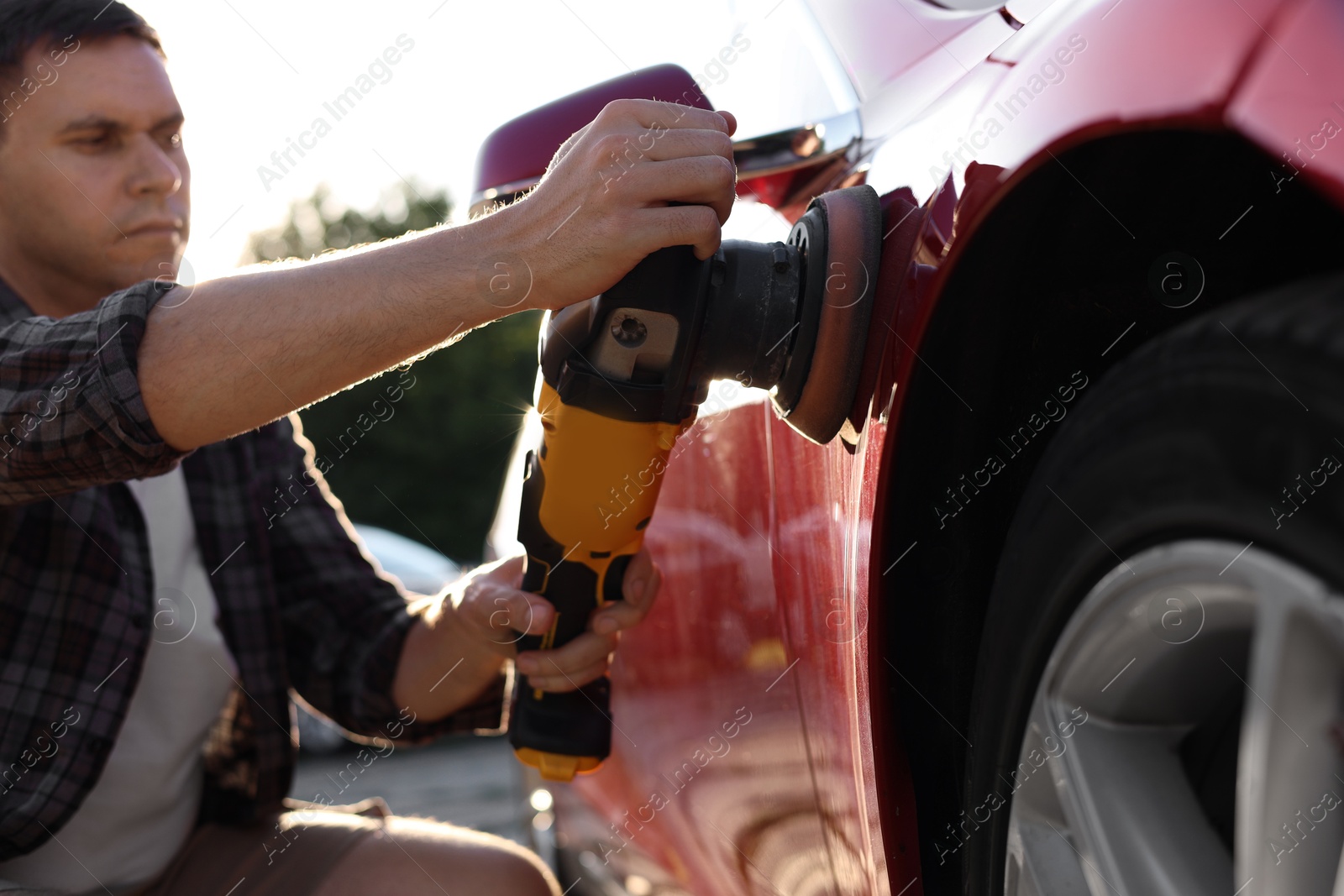 Photo of Man polishing car with orbital polisher outdoors