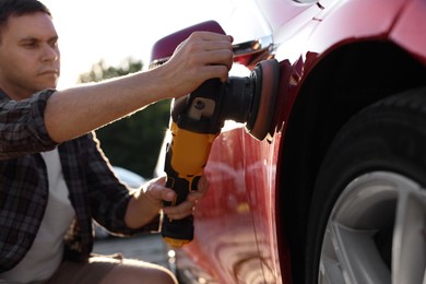 Photo of Man polishing car with orbital polisher outdoors