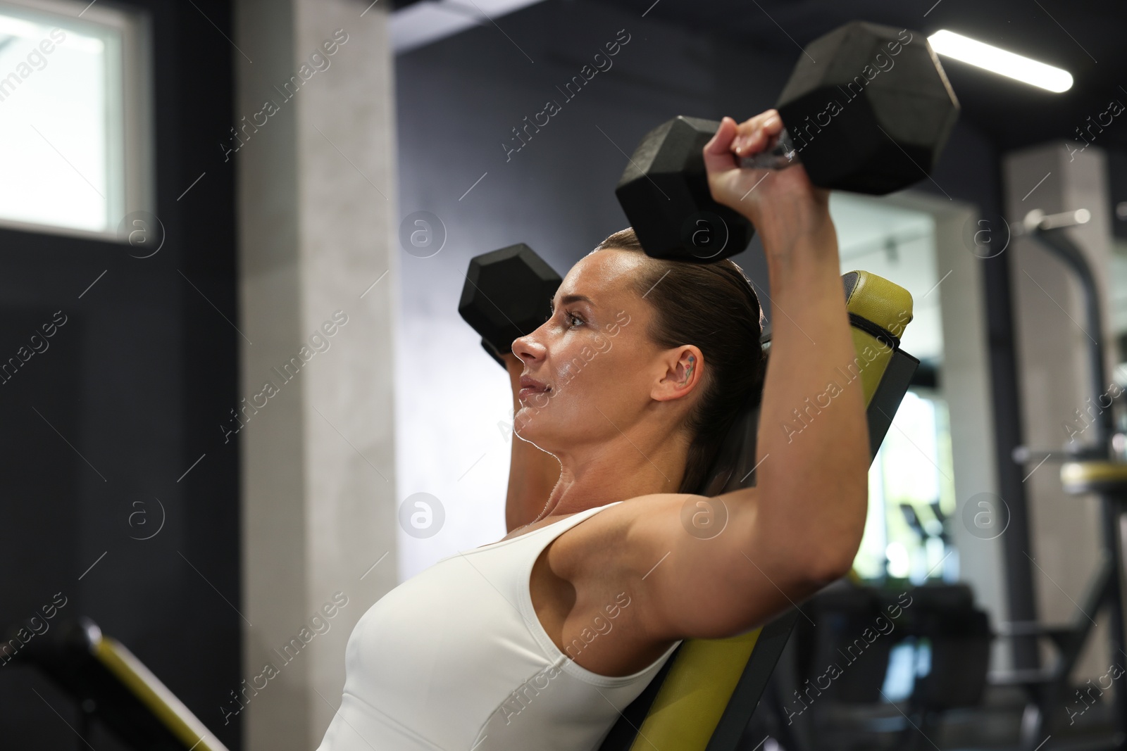 Photo of Athletic woman training with dumbbells in gym