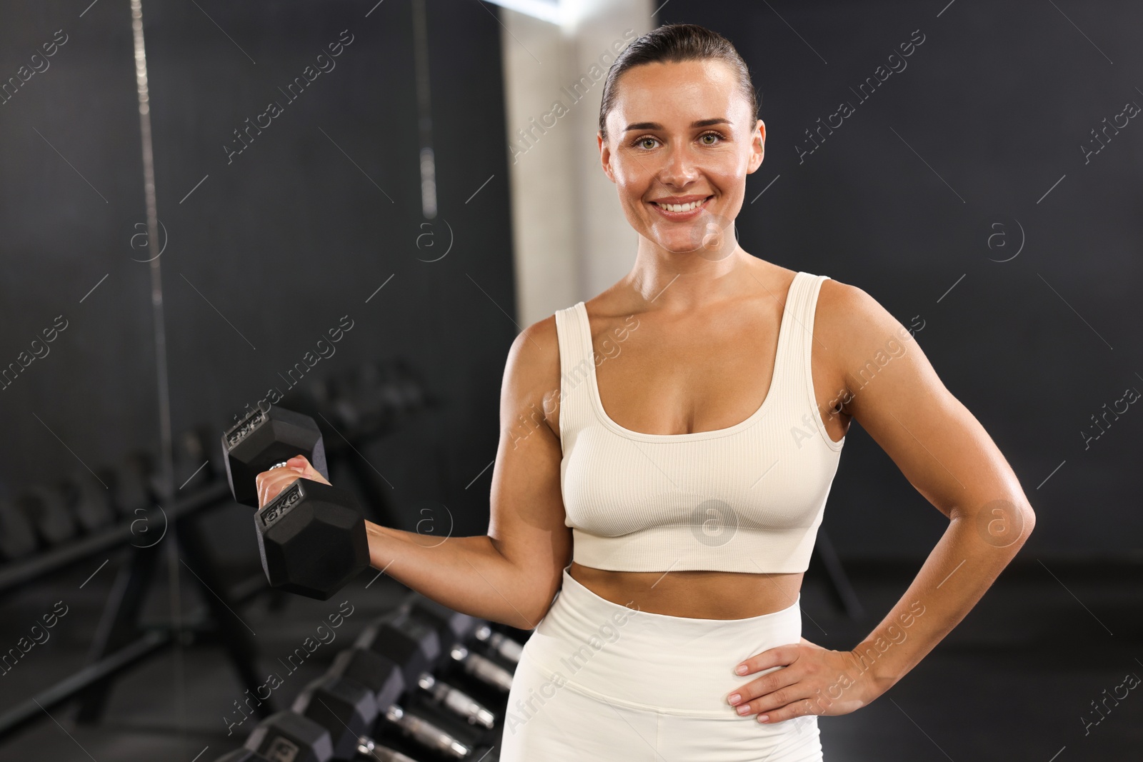 Photo of Smiling woman training with dumbbell in gym