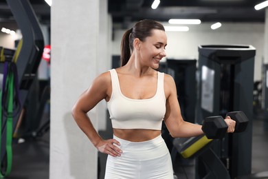 Photo of Smiling woman training with dumbbell in gym