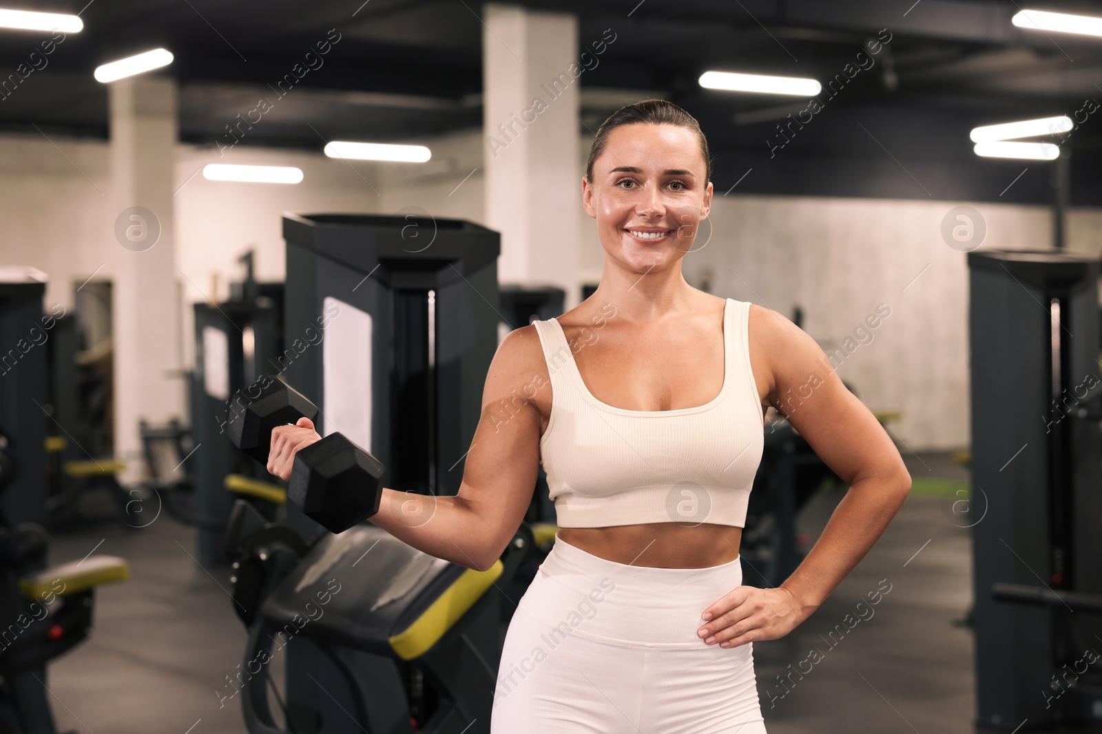 Photo of Smiling woman training with dumbbell in gym