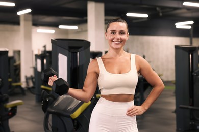Photo of Smiling woman training with dumbbell in gym