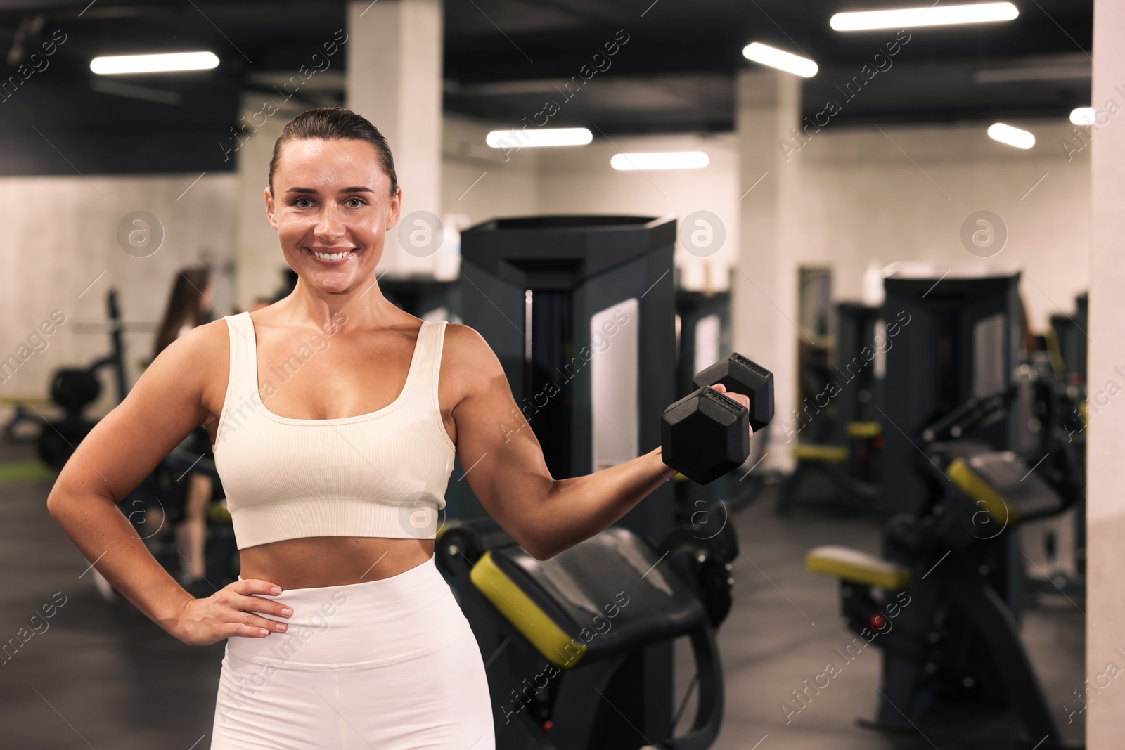 Photo of Smiling woman training with dumbbell in gym
