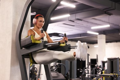 Photo of Athletic woman in headphones training on power tower in gym