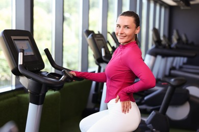 Photo of Smiling woman on exercise bike in gym