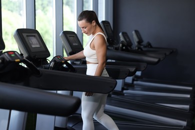Photo of Athletic woman training on treadmill in gym