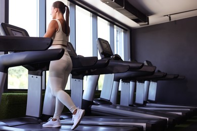 Photo of Athletic woman training on treadmill in gym, low angle view
