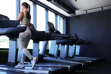 Photo of Athletic woman training on treadmill in gym, low angle view