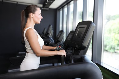 Photo of Athletic woman training on treadmill in gym
