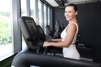Photo of Smiling woman training on treadmill in gym