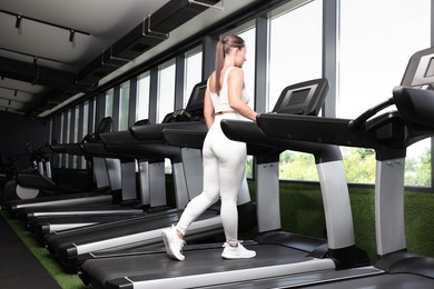 Photo of Athletic woman training on treadmill in gym, low angle view