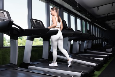 Photo of Athletic woman training on treadmill in gym, low angle view